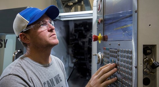 An engineer checks settings on his CNC mill prior to machining a part.