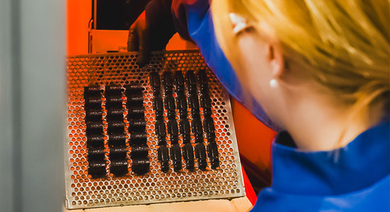 Woman in blue working with machinery, illuminated by a warm orange light.